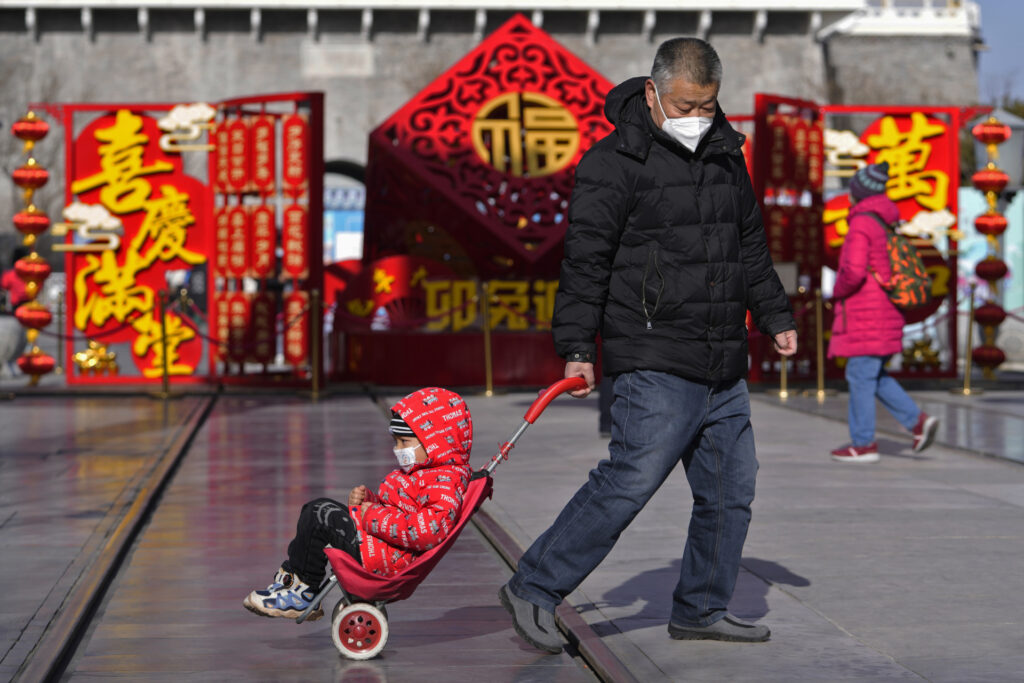 Un hombre tira de un niño junto a una decoración del Año Nuevo Lunar expuesta en la calle comercial peatonal de Qianmen